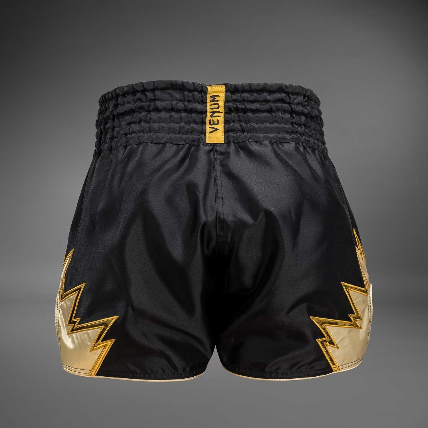 Short de Muay Thaï Venum Inferno noir et or, tissu léger et fentes latérales pour mobilité optimale.