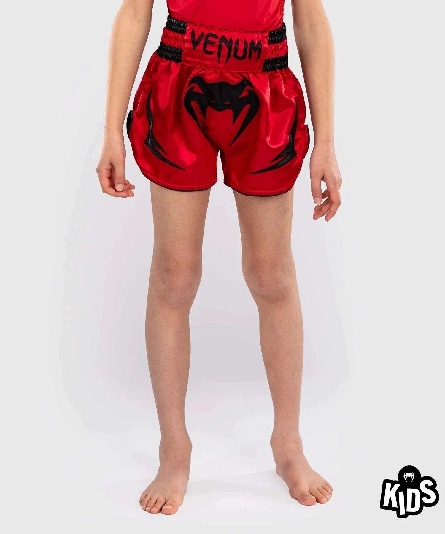 Red Venum Inferno kids Muay Thai shorts with black graphics and elastic waistband designed for junior martial arts training