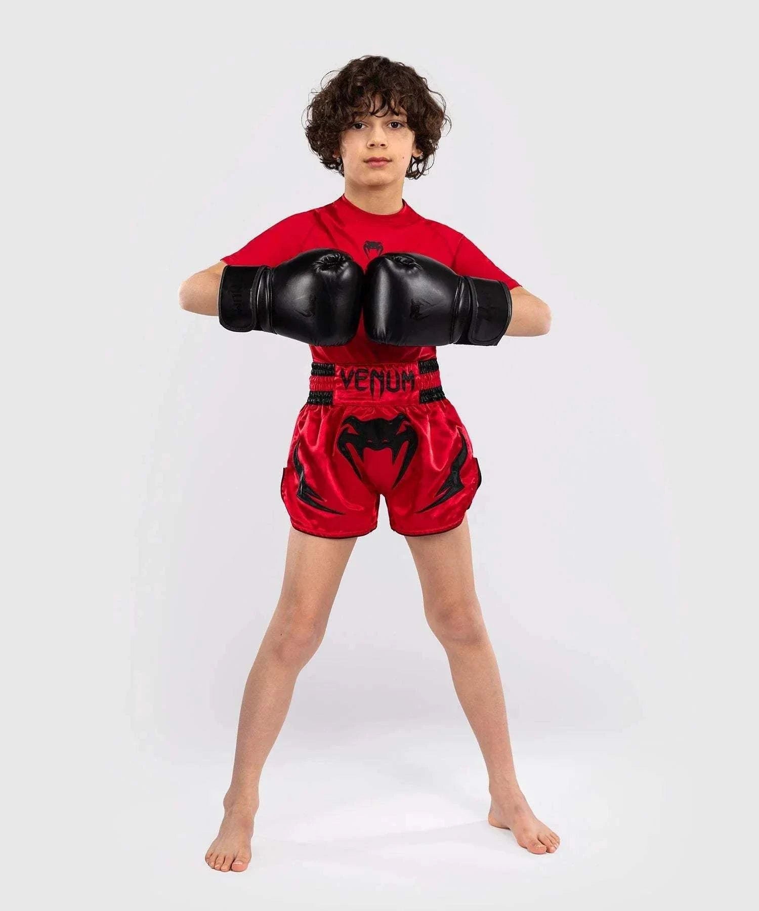 child wearing red Short Muay Thai Venum Inferno gloves and red top in fighting pose