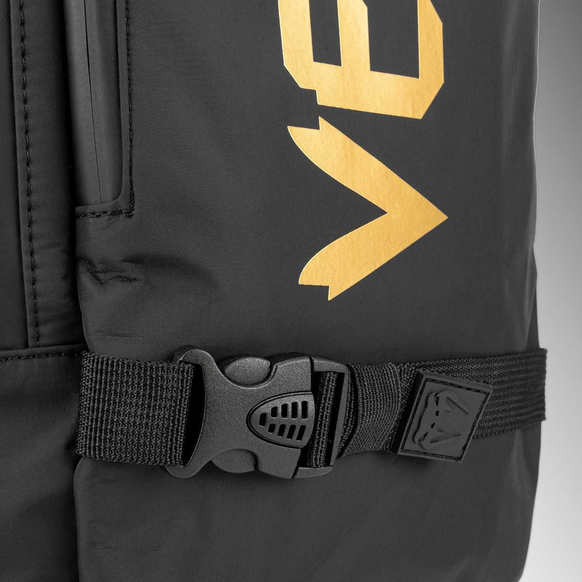 Sac à dos Venum noir en textile, avec logo doré, sangle horizontale et boucle de serrage noire.