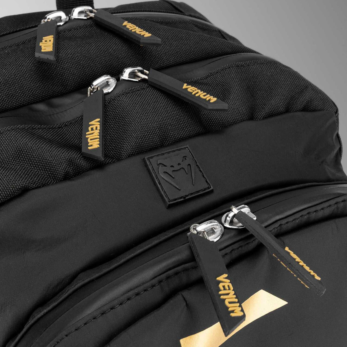 Sac à dos Venum noir en textile, avec détails dorés, multiples compartiments et logo caoutchouc emblématique