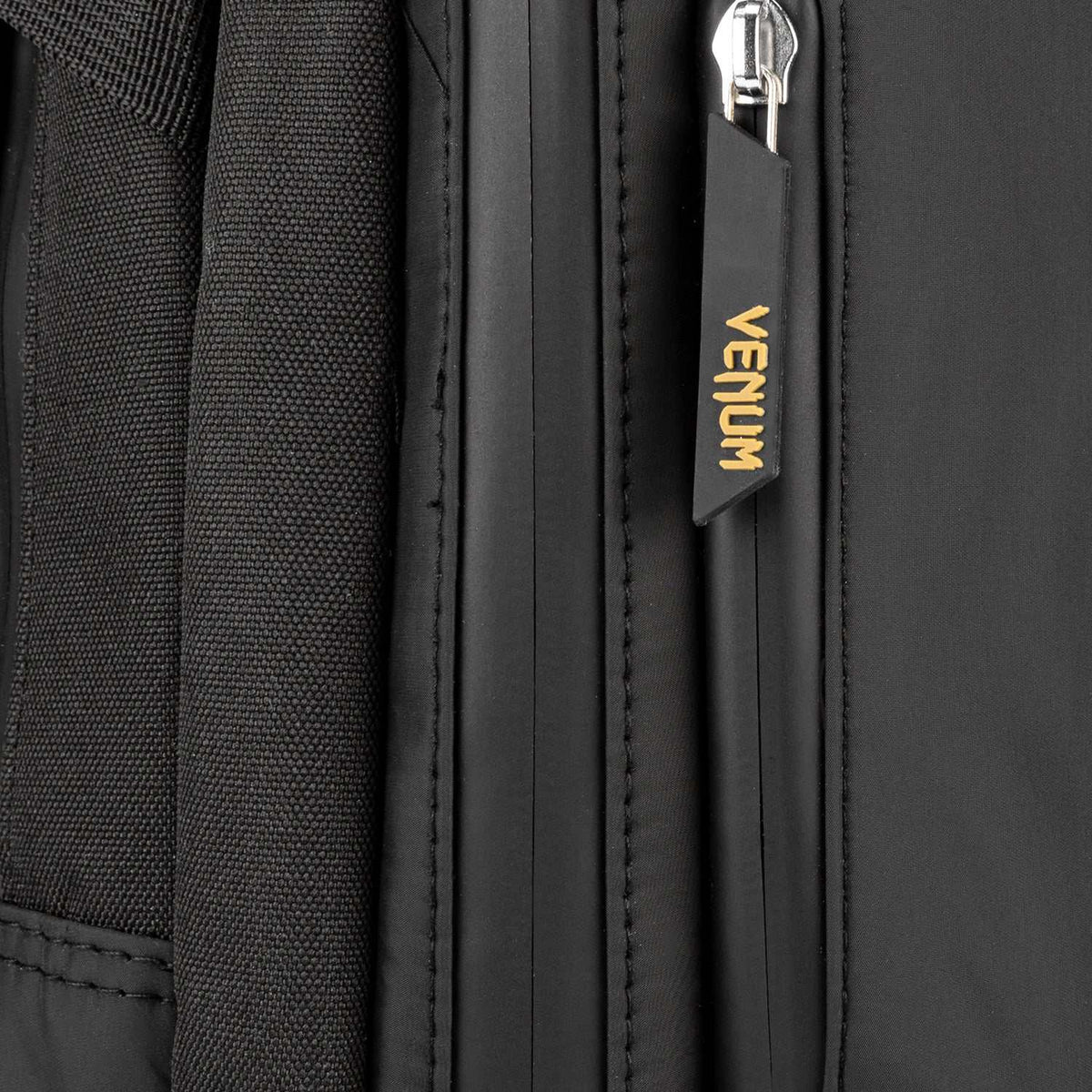 Sac à dos Venum noir en textile, avec fermeture zippée et tirette siglée Venum dorée.
