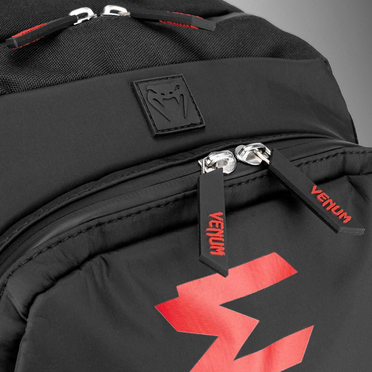 Sac à dos Venum noir en textile, détails rouges, logo imposant et fermetures éclair robustes apparentes.