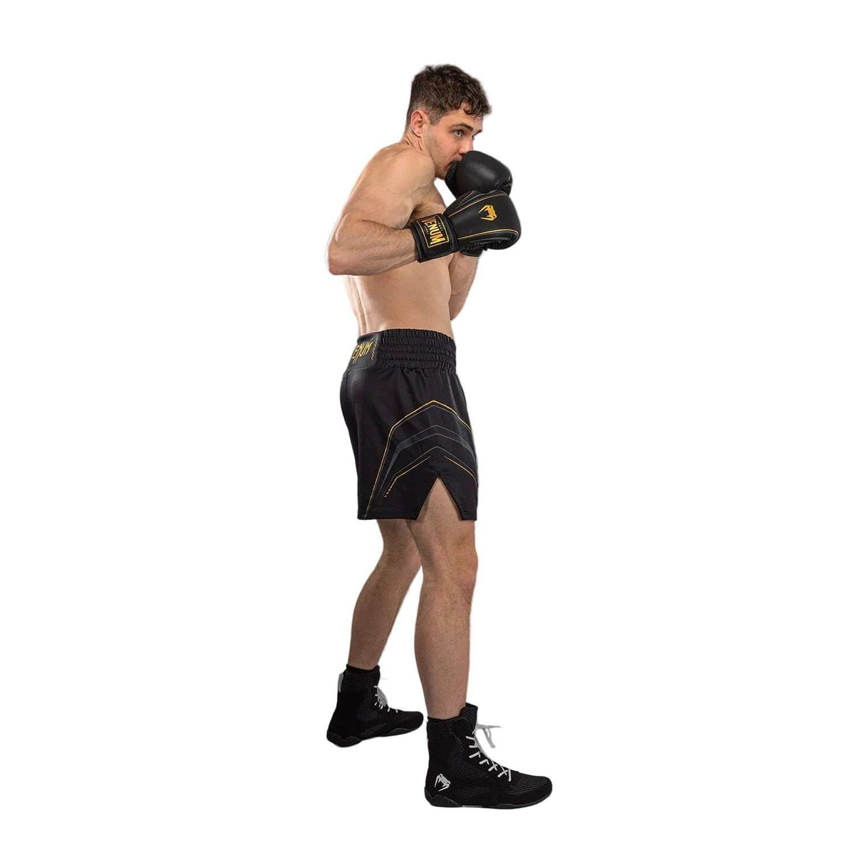 Short de boxe anglaise noir en tissu technique, orné de motifs dorés et d’une coupe ample au-dessus du genou.